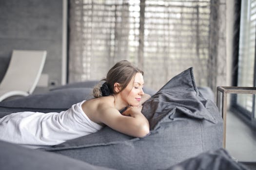 A serene moment indoors as a woman relaxes on a couch, enjoying a peaceful spa day. She has a self care day where she is finding peace.