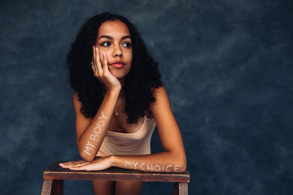 Portrait of a young woman with 'My Body My Choice' on arms, symbolizing self love and empowerment.