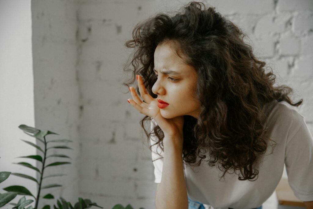 A thoughtful young woman with curly hair indoors, displaying a curious expression.