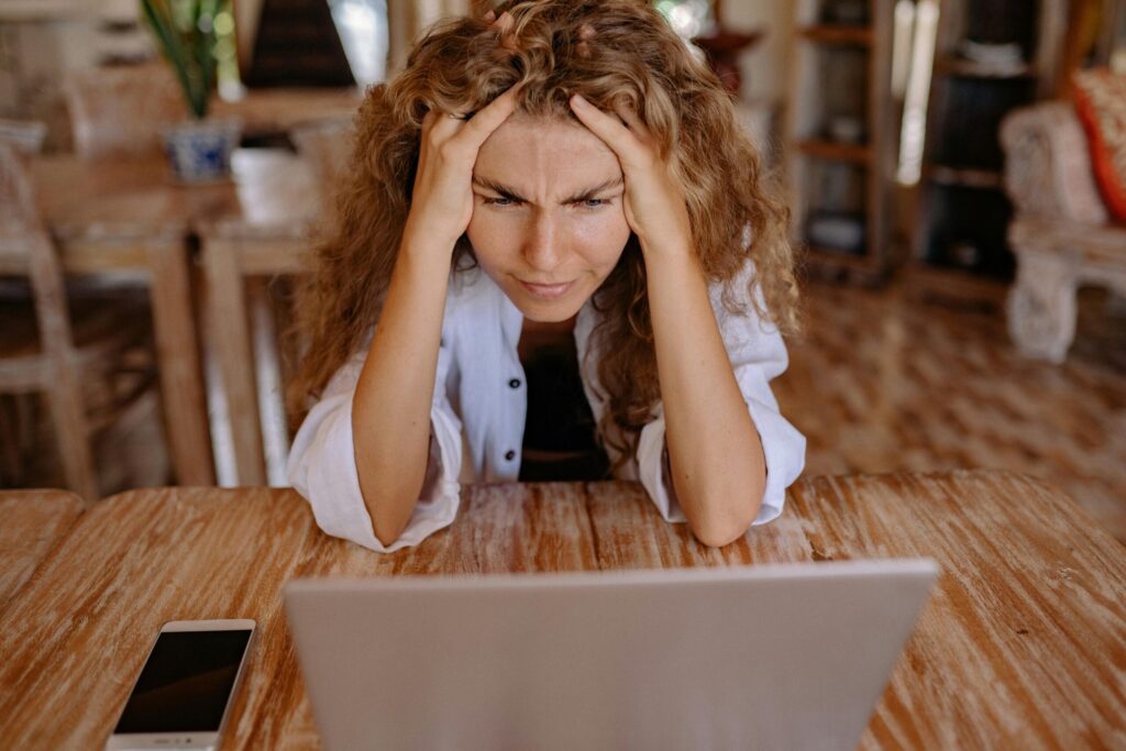 Stressed woman at home struggling with remote work on her laptop.