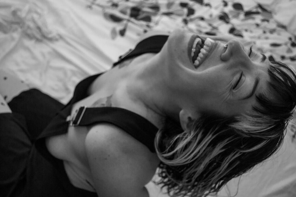 Black and white portrait of a smiling woman expressing joy with eyes closed.