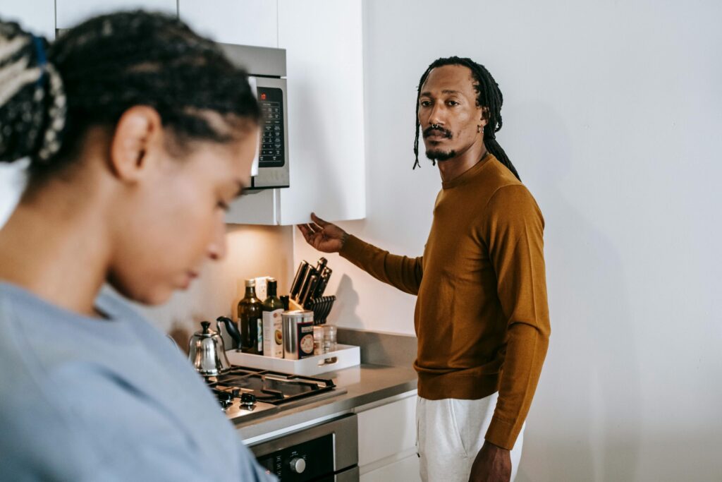 A young couple in their kitchen, visibly upset and in a tense discussion.