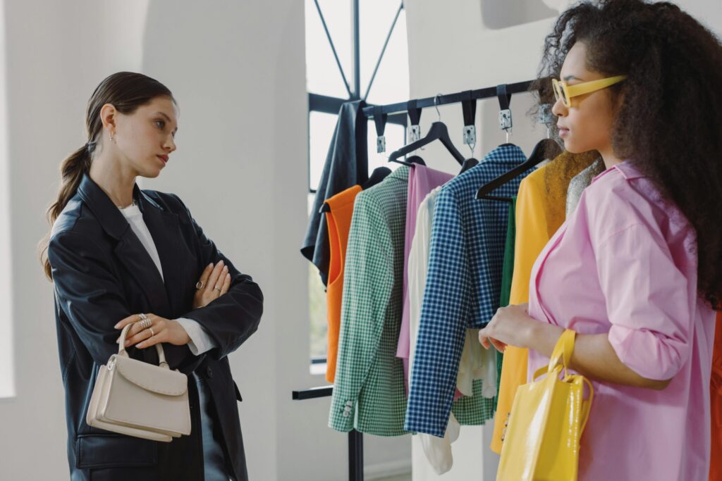 Two women browsing colorful clothing racks in a modern boutique.