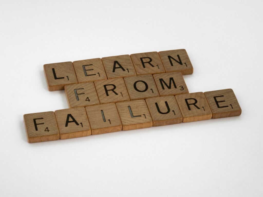Wooden Scrabble tiles spelling 'Learn from Failure' on a white background, promoting resilience.