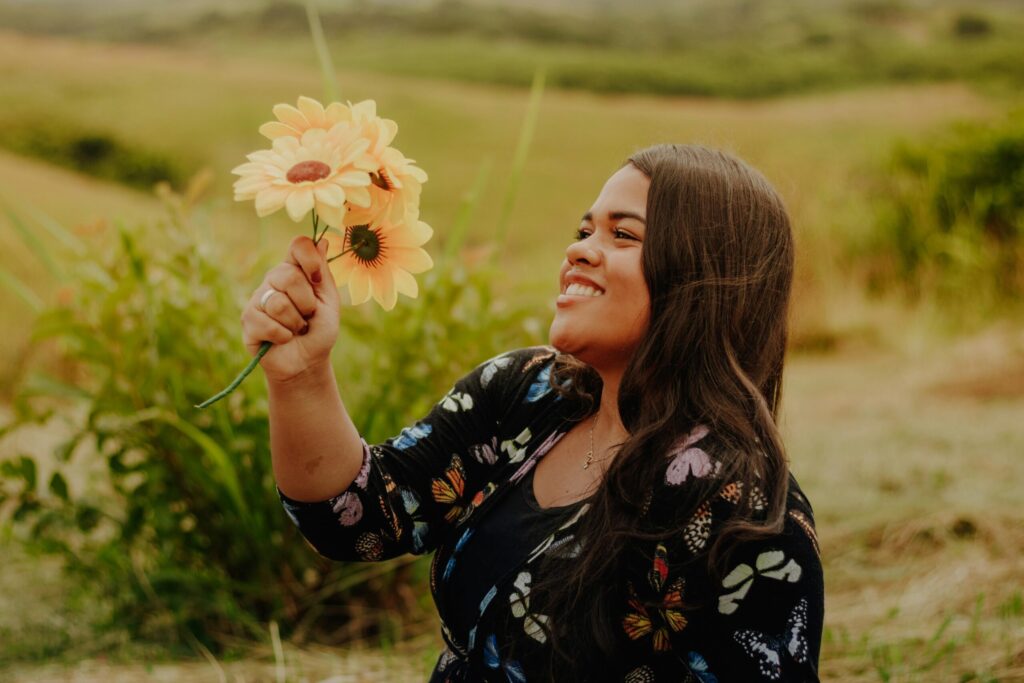 Smiling young woman holding sunflowers in a vibrant field.